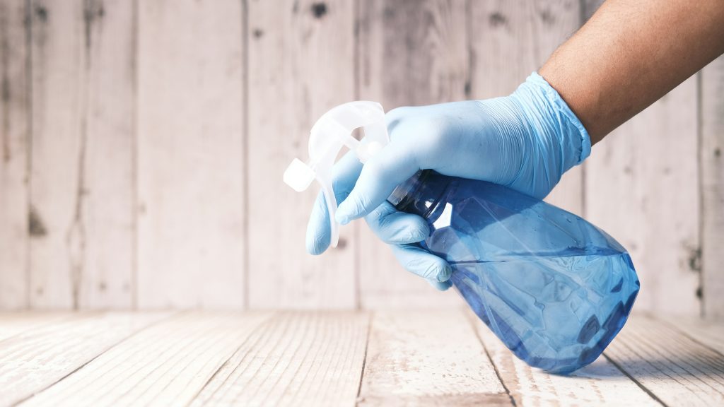 flacon transparent bleu tenu par une main avec des gants bleu