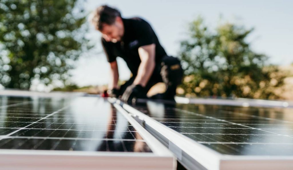 artisan qui pose une climatisation solaire sur un toit