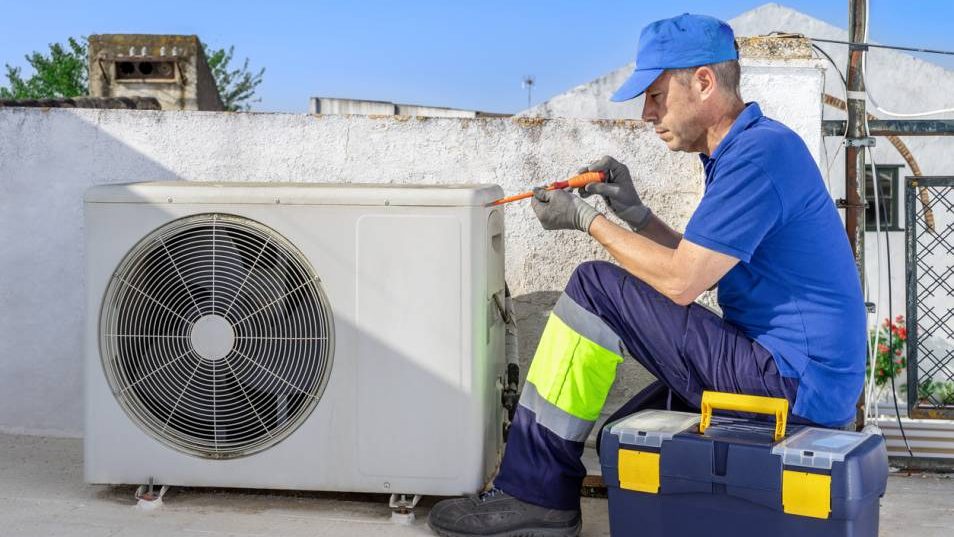 artisan qui bricole la climatisation sur le toit